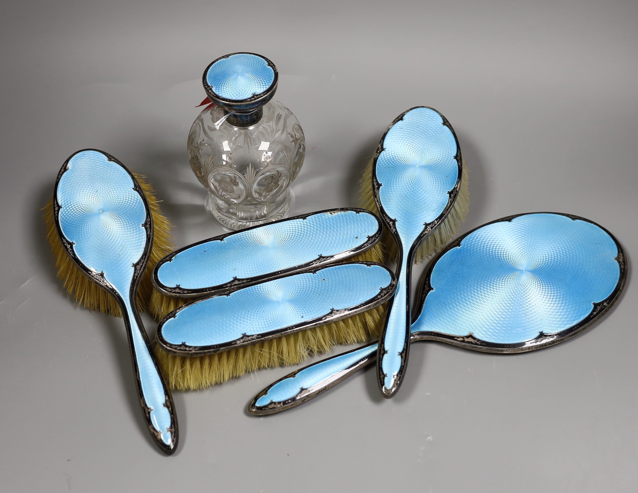 A George V silver and two colour enamel mounted blue enamel mirror and brush set, including a scent bottle, (a.f.).